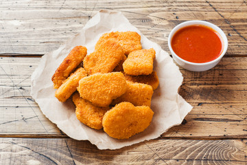 chicken nuggets with tomato sauce on wooden background. Copy space.