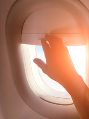 Passenger's hand closing the window shade on a modern airplane.