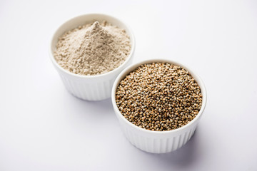 Bajra (pearl millet) / sorghum grains with it's flour or powder in a bowl, selective focus