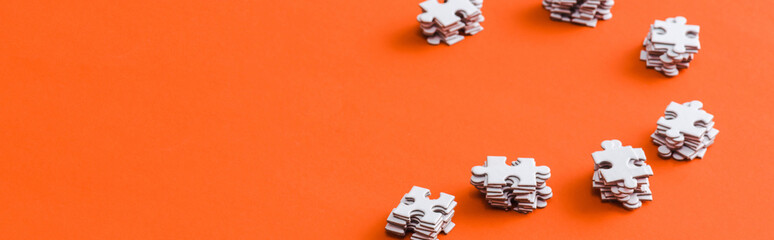 panoramic shot of stacks with white puzzle pieces on orange