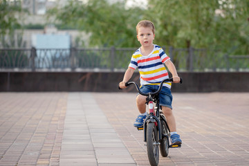 a child riding a bike in the city Park rides and smiles happily