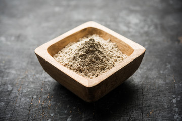 Bajra (pearl millet) / sorghum grains with it's flour or powder in a bowl, selective focus