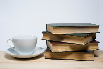 Books stacked in a pile and next to a mug on a white background. Reading books, school, library