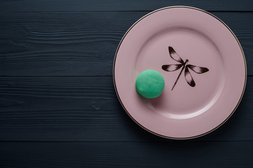 FRENCH CAKE MACARON MINT ON PINK PLATE ON GREY WOODEN BOARD FLAT LAY