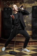 Young artistic man singing with microphone