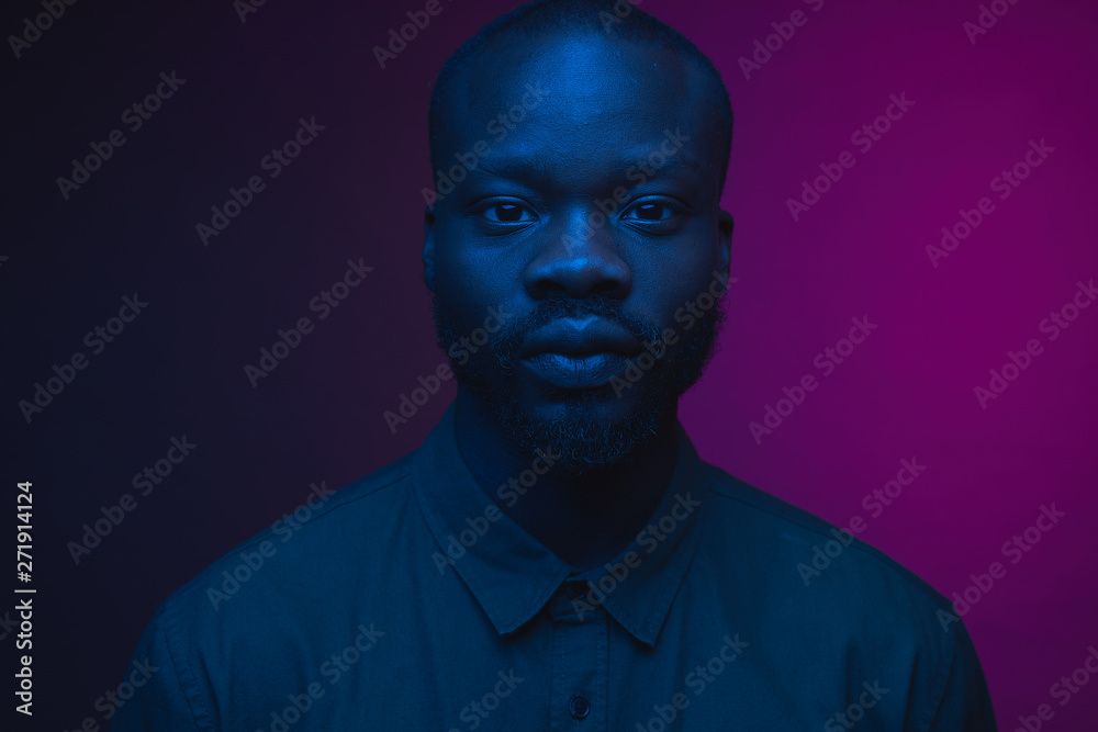 Wall mural Dark neon portrait of young man with beard, wearer in shirt. Pink and blue light. Technology