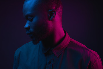 Dark neon portrait of young man with beard, wearer in shirt. Pink and blue light. Technology