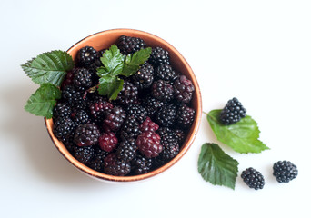 Black raspberries with leaves on a plate.