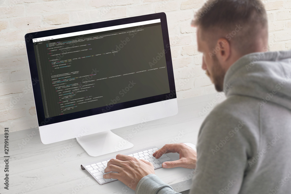 Poster Man coding app on a computer. Close-up scene. Clean office desk with brick wall in background.