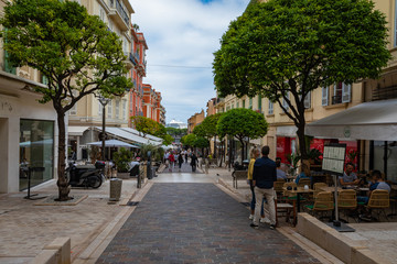 People walking through a narrow street in the center of Monaco on the French Riviera.