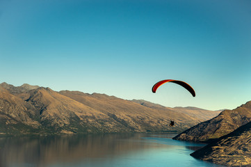 Paraglider flying in blue sky with gorgeous mountain view at Queenstown in South Island, New...