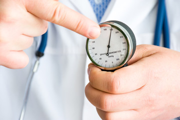 Doctor shows to patient and points finger at arrow of mechanical sphygmomanometer, which in turn...