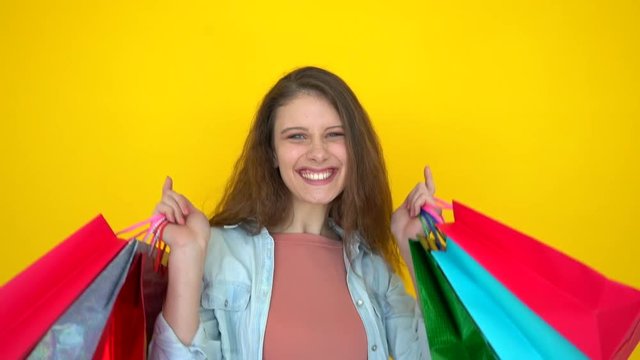 shopping girl, shopping bags. Portrait of shopaholic girl with colorful shopping bags in hands indoors on yellow background. Happy beautiful young smiling shopping woman female customer shoper sale