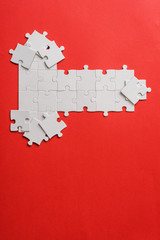 top view of white connected puzzle pieces near shapes on red