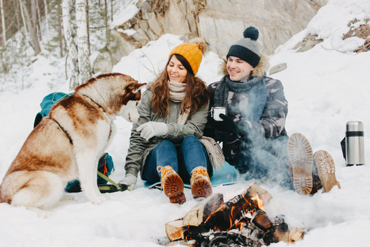 The happy couple with dog haski at forest nature park in cold season. Travel adventure love story