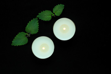 White burning tealight candles on black background. Beauty, SPA treatments, massage therapy and relax concept.
