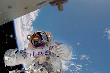 Astronaut gives push upps to the camera in outer space. Earth is on the background. ELemnts furnished by NASA.
