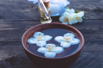 Obraz na płótnie Canvas Jasmine essential oil and flowers on wooden table background.