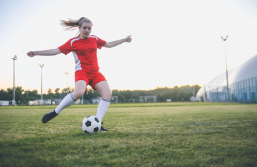 Obraz na płótnie Canvas Close up of female soccer player kicking the ball at the goal