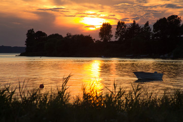 Leuchtender Sonnenuntergang nach Gewitter am See mit Boot ind Skandinavien, Dänemark - Brilliant sunset after thunderstorm at the lake with boat in Scandinavia, Denmark