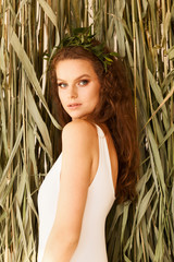 Fototapeta premium Beautiful sexy young woman in white swimsuit near dry tropical cane plants. Retreat, relaxation concept. Organic body care in summer holiday. Copy space image.