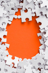 top view of frame of white puzzle pieces on orange with copy space