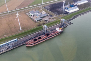 Fototapeta na wymiar Dutch harbor Eemshaven with wind turbines and and freighter transporting coals