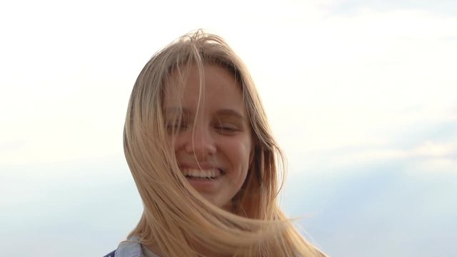 Close up portrait of pretty blonde woman outdoors. Smiling and looking at camera.