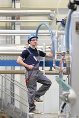 Industriearbeiter in einer modernen Fabrik - Interieur Closeup mit Maschinen und Rohrleitungen //...