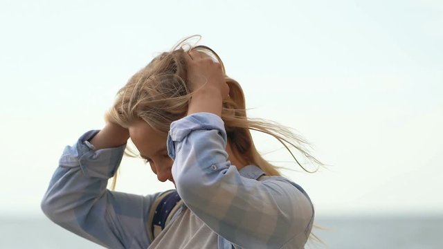 Happy blode woman outdoors. Waving blonde hair, smiling.