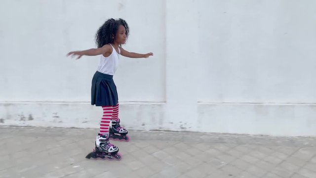 Little girl skating by the street. Afro girl outdoor