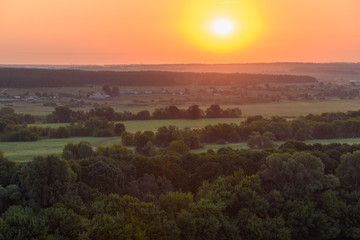 Sun rises in the early morning over the fields and forests