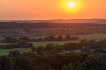 Sun rises in the early morning over the fields and forests