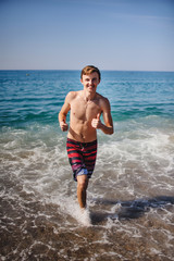 Fototapeta na wymiar Beautiful young happy man Running along the waves in water at the sea beach. Turkey. Vacation. Sunlight. Place for text Close up. Summer vacation, honeymoon. Ocean sea