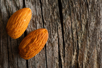 two peeled almonds on old wood table