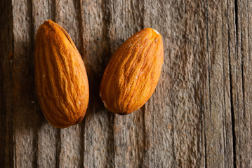 two peeled almonds on old wood table