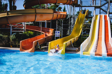 Happy young man falling into water. sitting in tube on hill.  Roll with a water slide in the pool at a water park. Thumb up. Summer vacation, honeymoon. Sunlight. Jumps. Turkey. vacation. close up