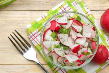 Fresh radish and cucumber salad and greens on a natural wooden table. Salad of spring vegetables. ingredients for making salad. top view