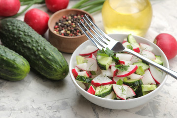 Fresh radish and cucumber salad and greens on a light concrete table. Salad of spring vegetables. ingredients for making salad.