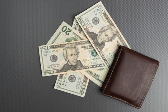 Dollar bills on gray background. Men's leather wallet with dollar bills.