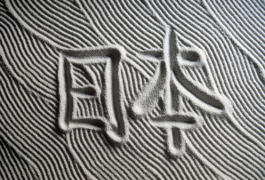Japanese Zen garden raked with the Chinese characters for Nihon (English translation: Japan) in capital letters in textured white sand