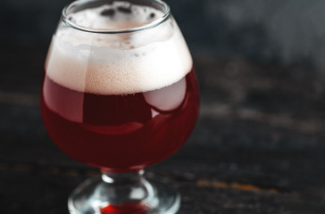 Cherry beer in a small glass on a dark concrete background close-up