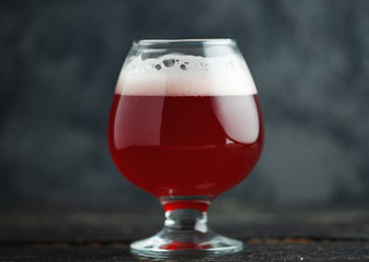 Cherry beer in a small glass on a dark concrete background close-up
