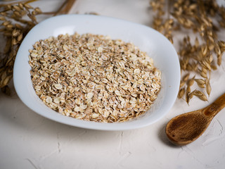 Oat flakes and ears of oats. Oatmeal in a plate on the table. Healthy breakfast