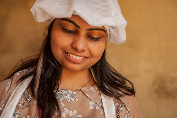 Attractive Indian woman cook cuts vegetables by knife. Closeup portrait of young beautiful woman....