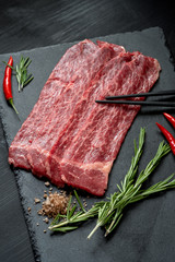 Pieces of raw marble beef black Angus for grilling on a stone Board on a dark background. Meat for yakiniku top view
