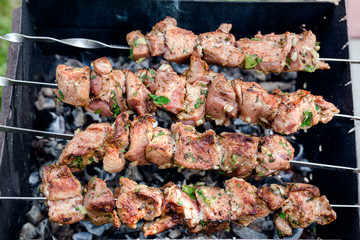 The process of cooking raw meat on skewers