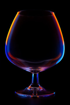 Glass for cognac, liqueur on a black background, multi-colored contours.