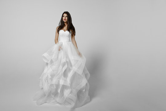 Fashionable bride in white dress, isolated on a white background, shooting in studio. Horizontal view.