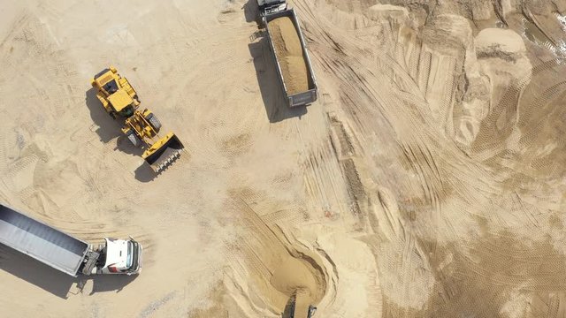 Aerial view loading bulldozer in open air quarry. Sand mining industry. Bulldozer machine. Crawler bulldozer moving at sand mine. Mining machinery working at sand quarry. 